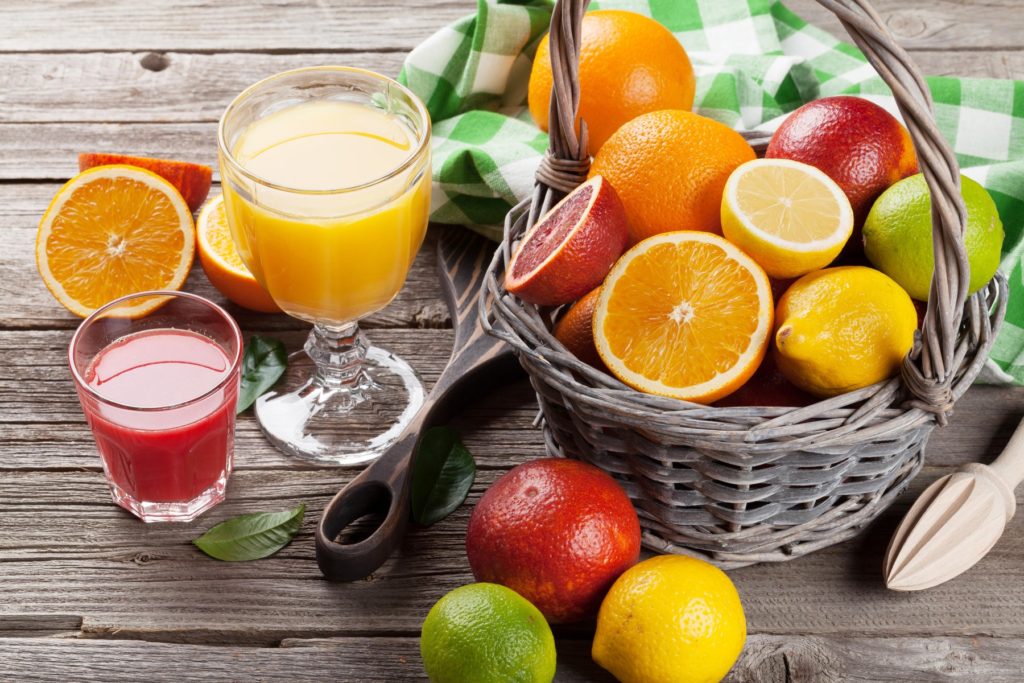 Citrus fruits in basket and juice glasses. Orange, lemon, lime.