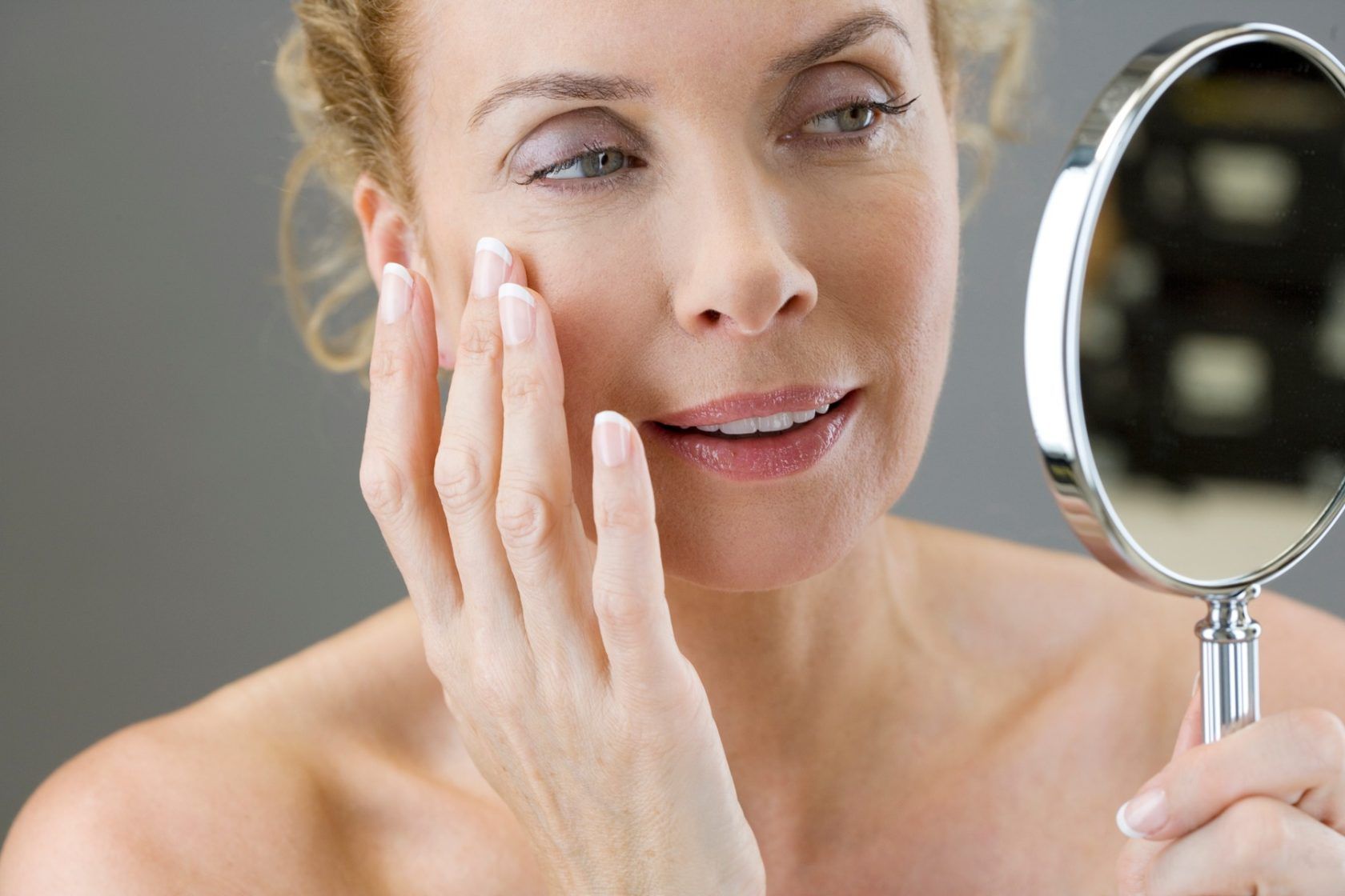 A middle-aged woman looking at her face in the mirror