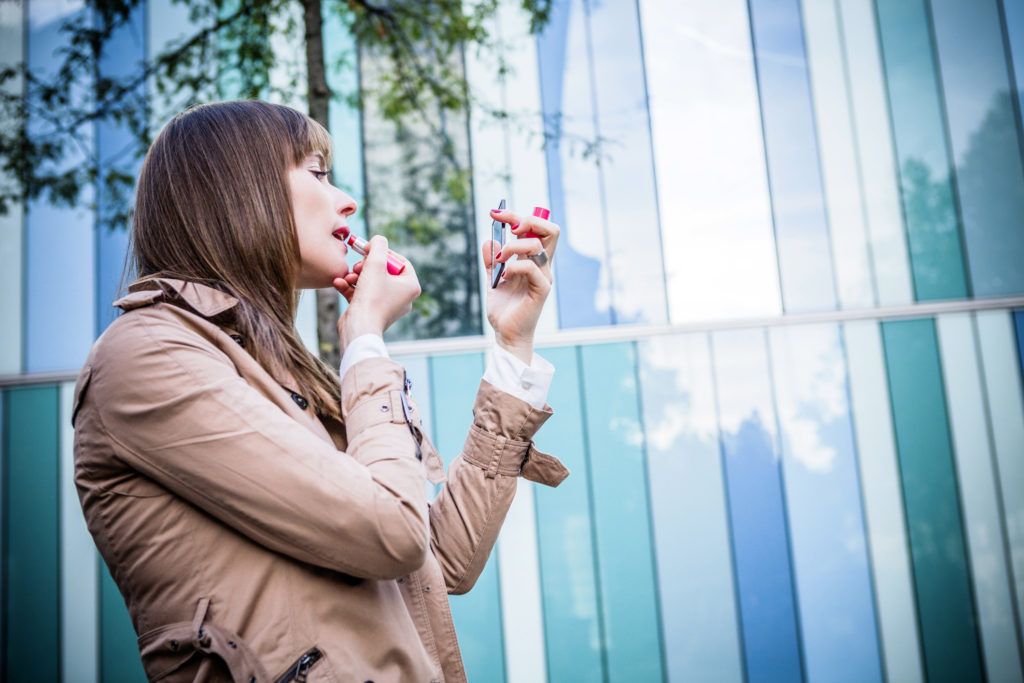 Young woman applying red lipstick, Munich, Bavaria, Germany