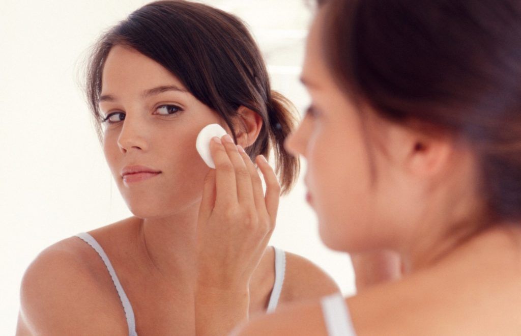 Teenage girl wiping face with pad