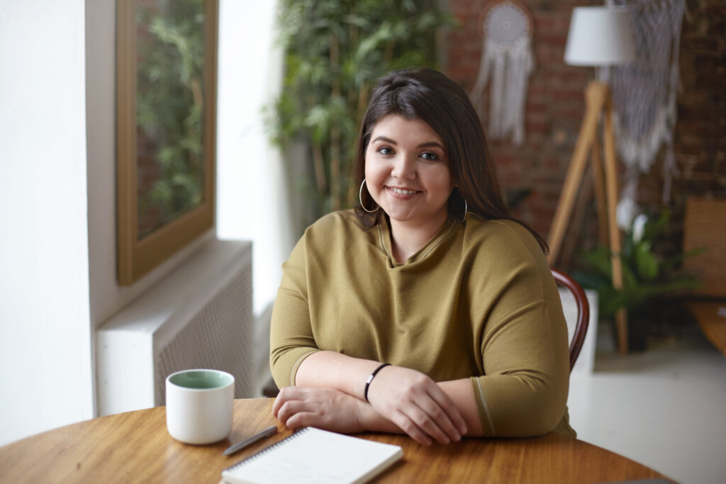 Lijepa žena s viškom kilograma pije kavu