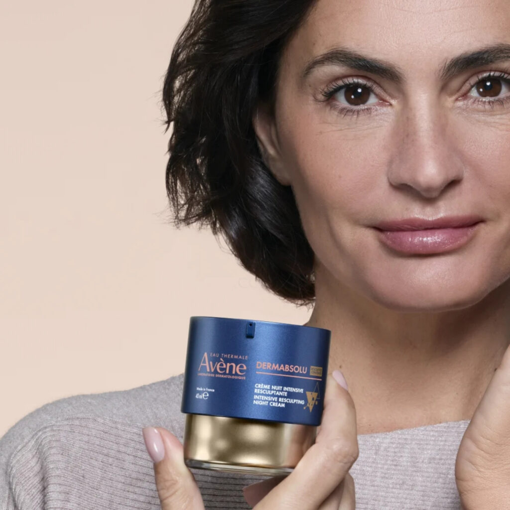 Žena nanosi Avène DermAbsolu noćnu njegu na lice prije spavanja.