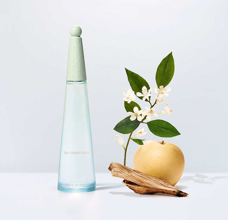 L'Eau d'Issey Eau Essentielle u minimalističkoj kompoziciji s kruškom, cvjetovima i drvom