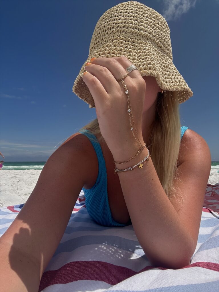 Žena sa slamnatim šeširom odmara na plaži tijekom sunčanog ljetnog dana