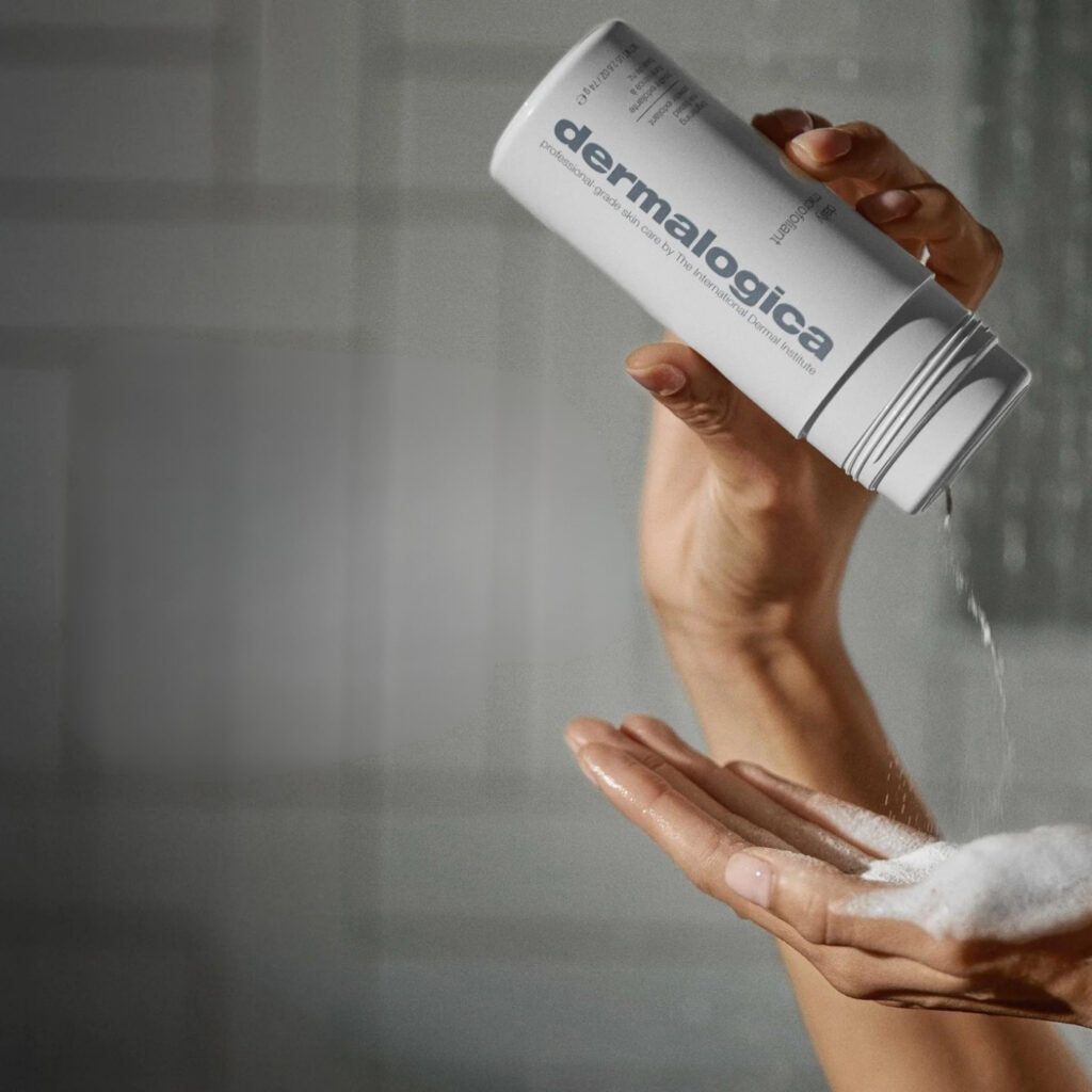 Nanošenje Dermalogica Daily Microfoliant pudera iz bočice u vlažne dlanove prije aktiviranja vodom