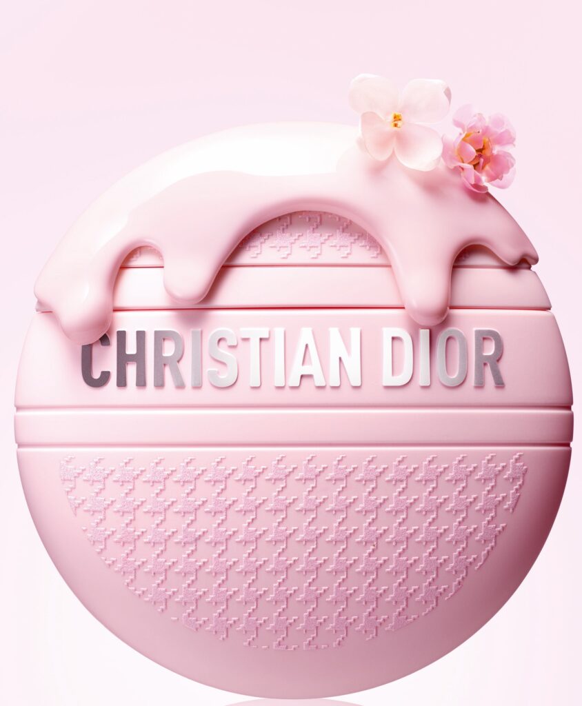 Krupni kadar okrugle Christian Dior kreme za ruke u ružičastoj ambalaži s pepita uzorkom i bijelim cvjetovima
