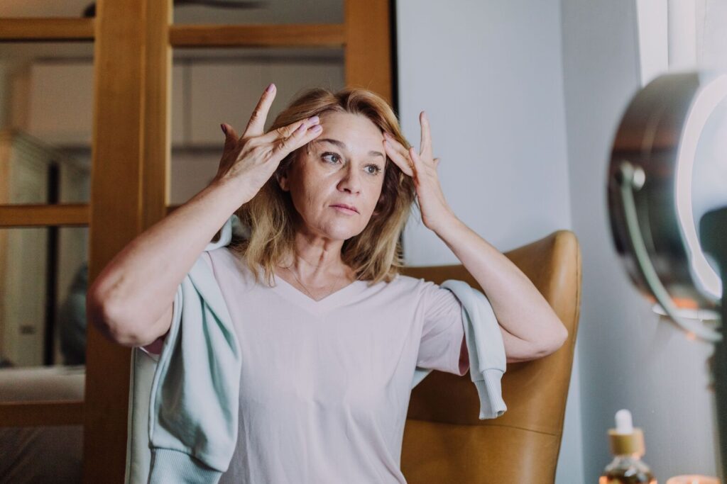 Žena se gleda u ogledalo i zateže lice