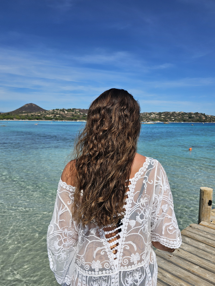 Žena na plaži s kosom izloženom suncu i morskoj vodi