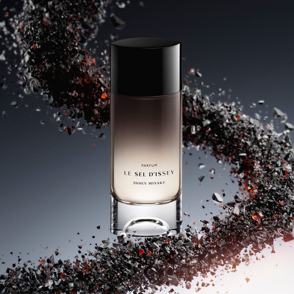 Bočica Le Sel d’Issey Parfum Issey Miyake okružena tamnim mineralnim fragmentima