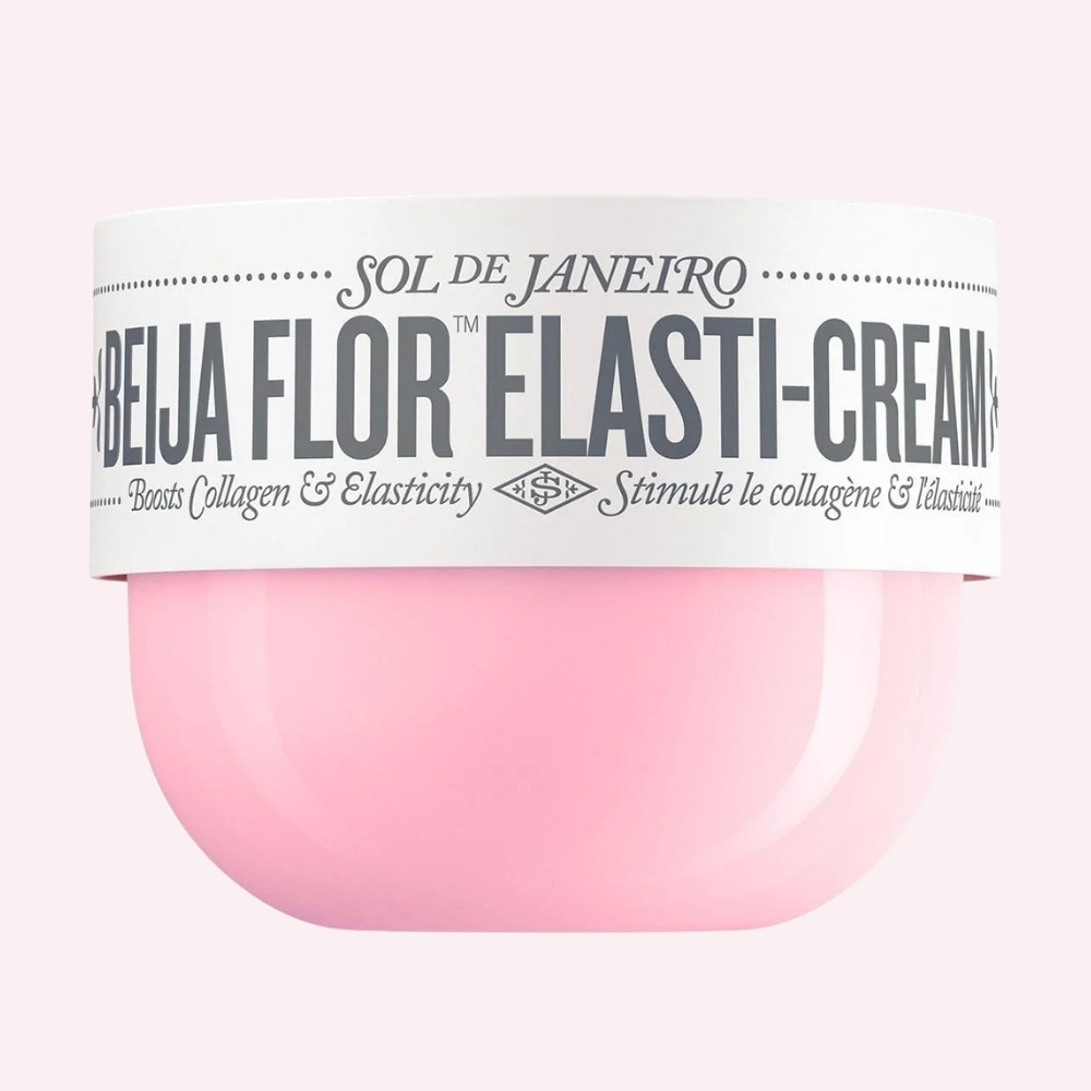 Sol de Janeiro Beija Flor Elasti-Cream u ružičastoj posudici s bijelim poklopcem na nježno ružičastoj pozadini.