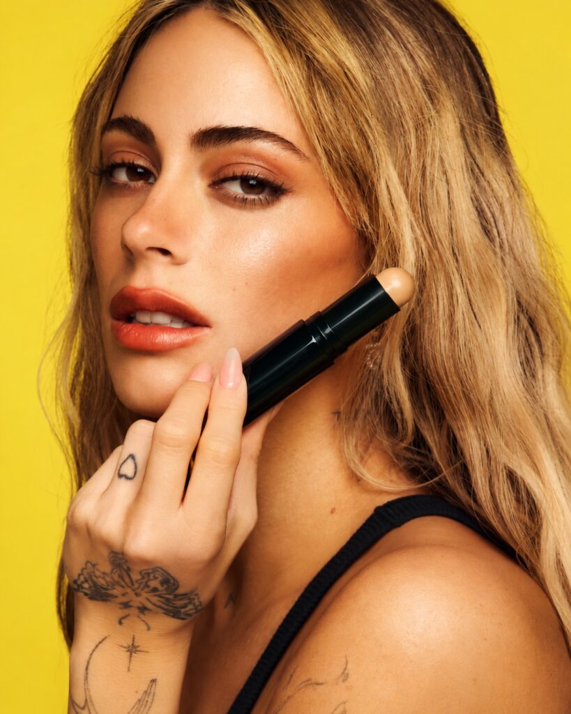 Žena drži otvoreni M·A·C Studio Radiance Skin Tint Stick uz lice